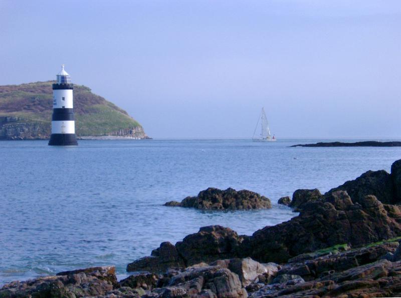 Lighthouse off a headland on the coast of Anglesey, Wales to warn shipping of a hazard