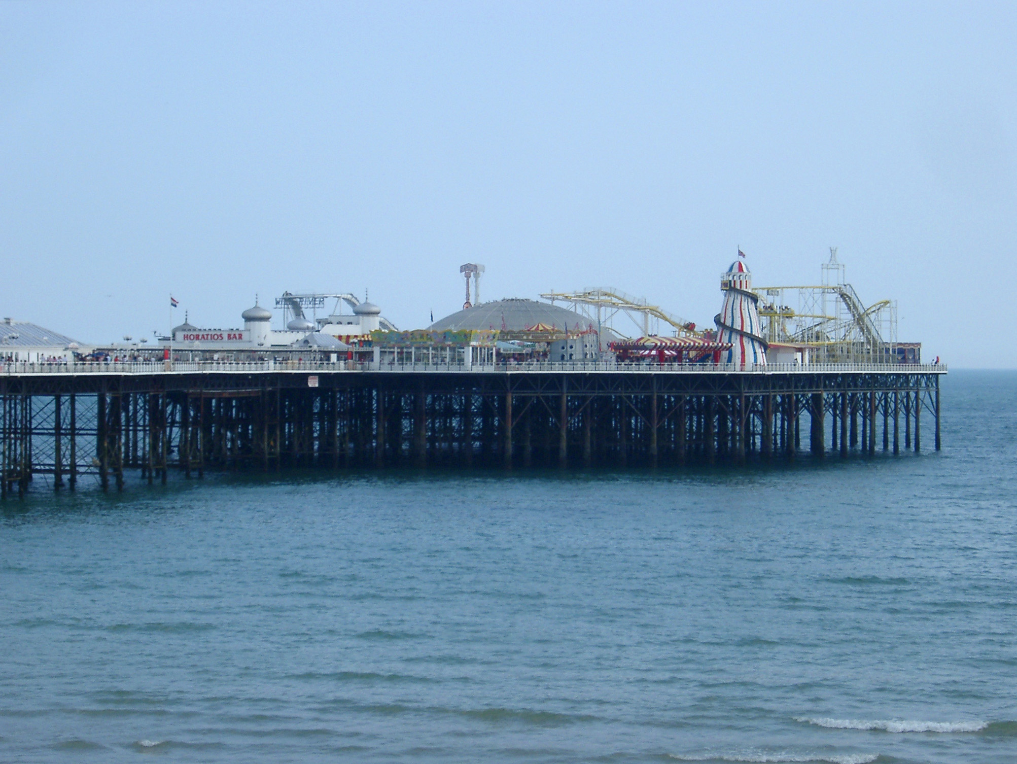 an image of View across the water of the Brighton Pier with its historical buildings now housing an amusement park and popular tourist attraction