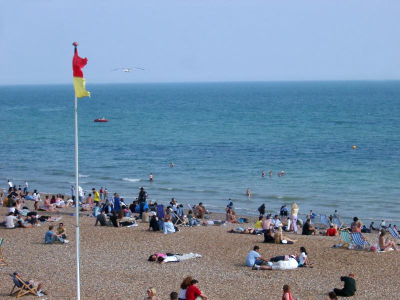 Tourists Relaxing at Beautiful Brighton Beach in England.