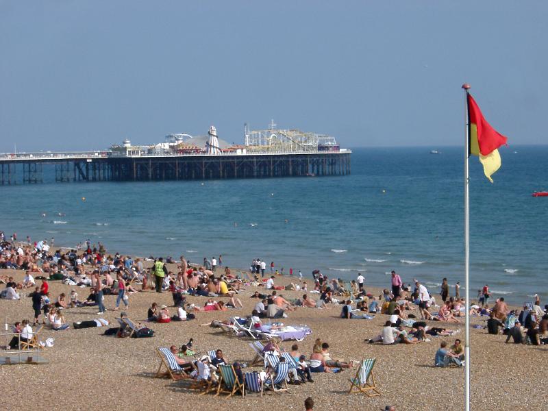 Tourists Relaxing at the Seaside Near the Famous Brighton Pier, also known as Palace Pier, Located in England.
