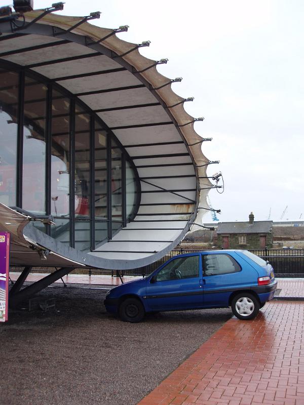 Blue Small Car at Famous Architectural Cardiff Bay Visitor Centre Tube at Cardiff Bay, Wales.