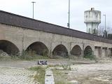 Old grungy obsolete railway bridge with arches in urban wasteland with a concrete water tower