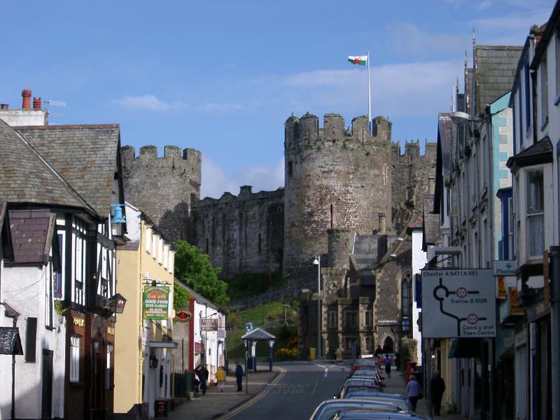 Street scene in Conway, Wales with a road sign, quaint historical buildings and the towers of the medieval stone castle in the background