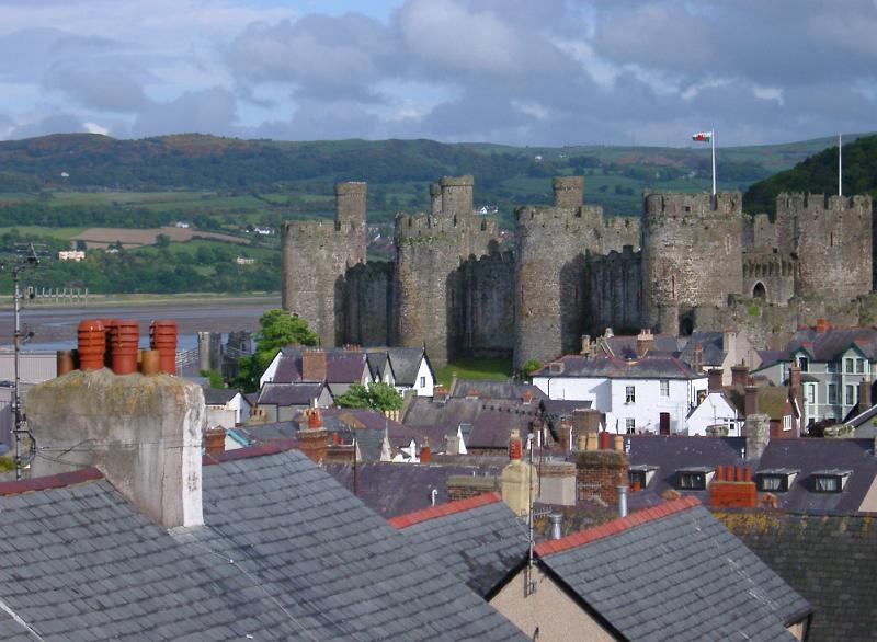 View over Conway rooftops to the historic stone castle and open Welsh countryside behind