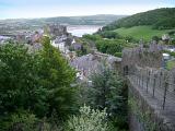 Historic crenellated stone walls surrounding the walled town of Conway, Wales with a scenic view down to the coast