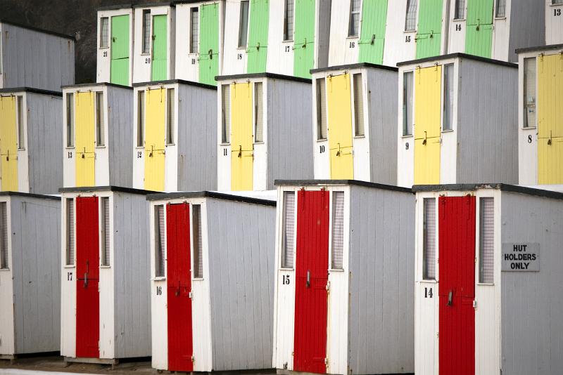 rows of beach huts at newquay with brightly painted doors
