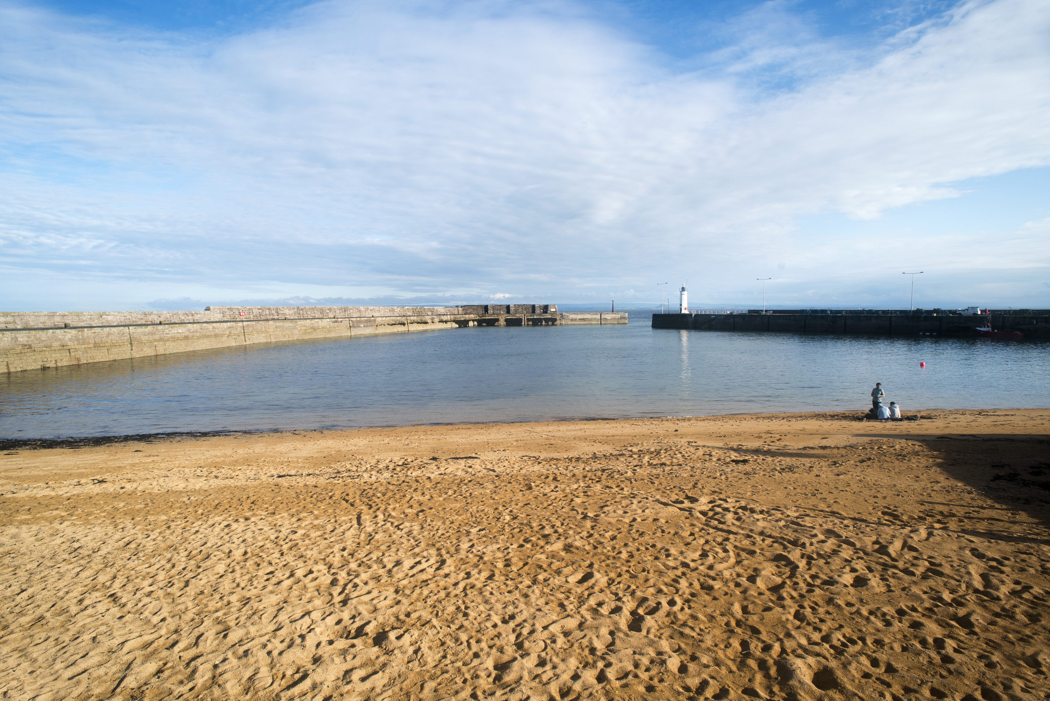 an image of Marine harbour Anstruther, Scotland at low tide looking out towards the entrance and lighthouse beacon