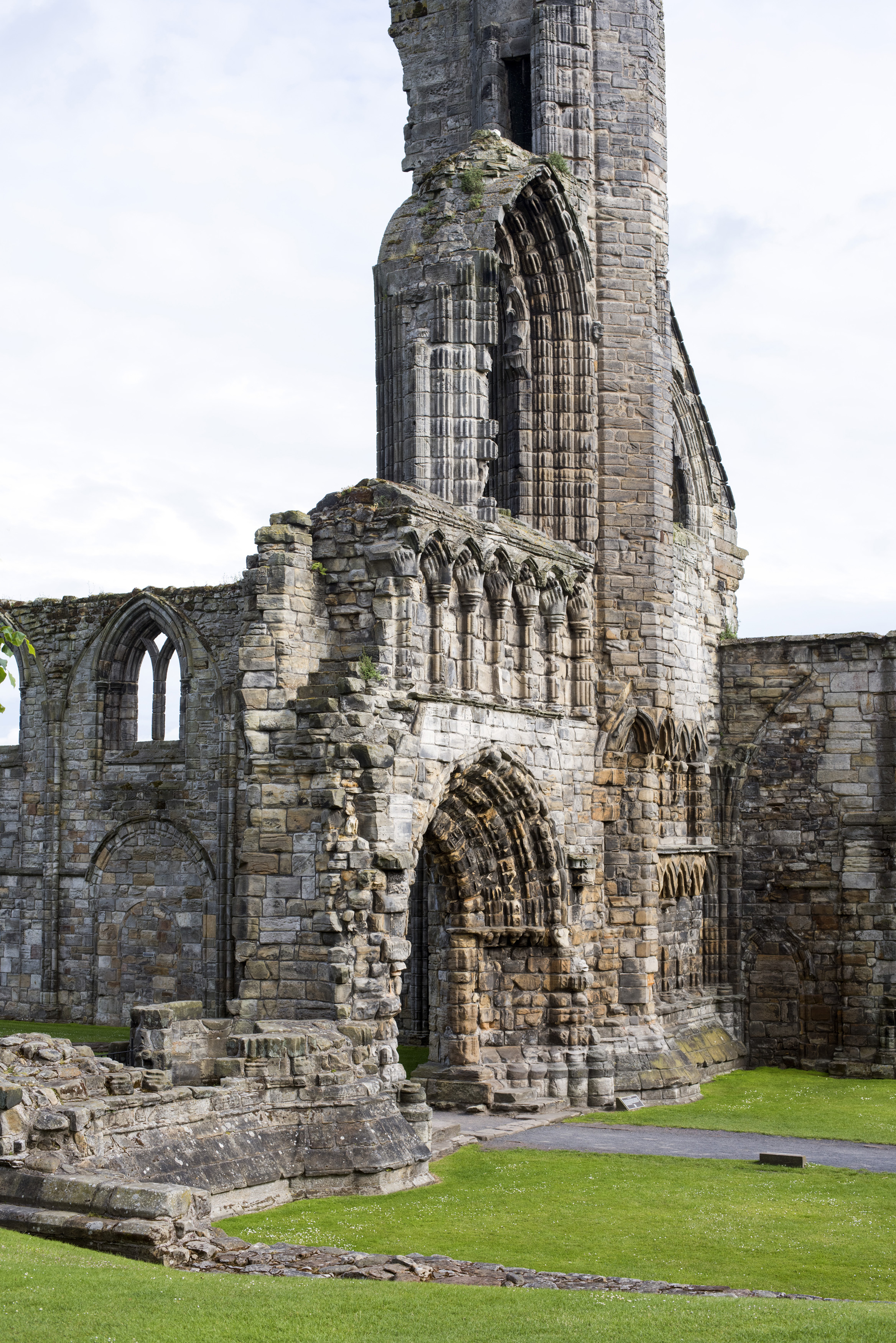 an image of Graceful Gothic stone arches and remnants of wall in St Andrews Cathedral ruins, Scotland against a grey sky with copy space