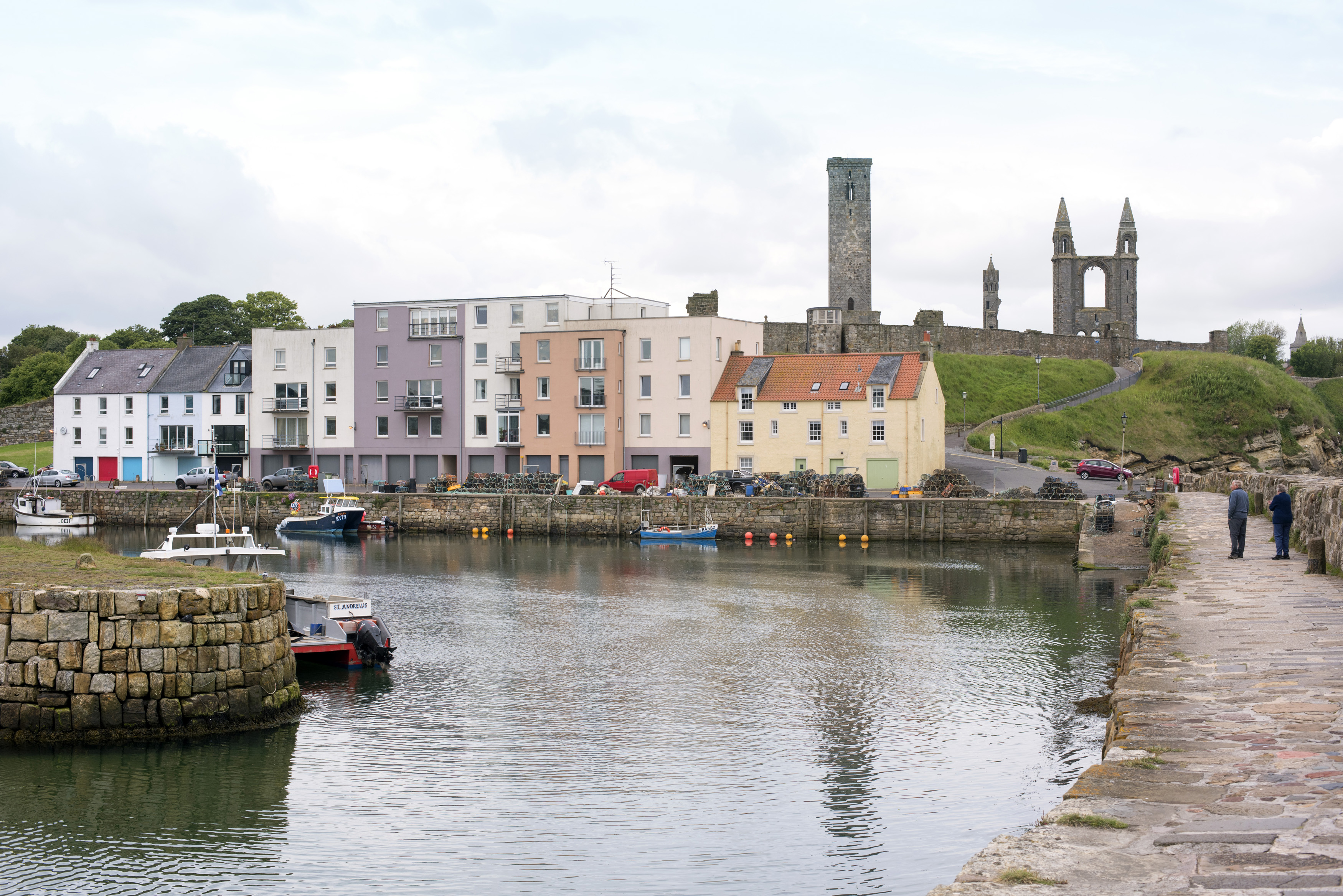 an image of Cute little European fishing harbor with quaint storefronts and apartments near Saint Andrews cathedral ruins in Scotland