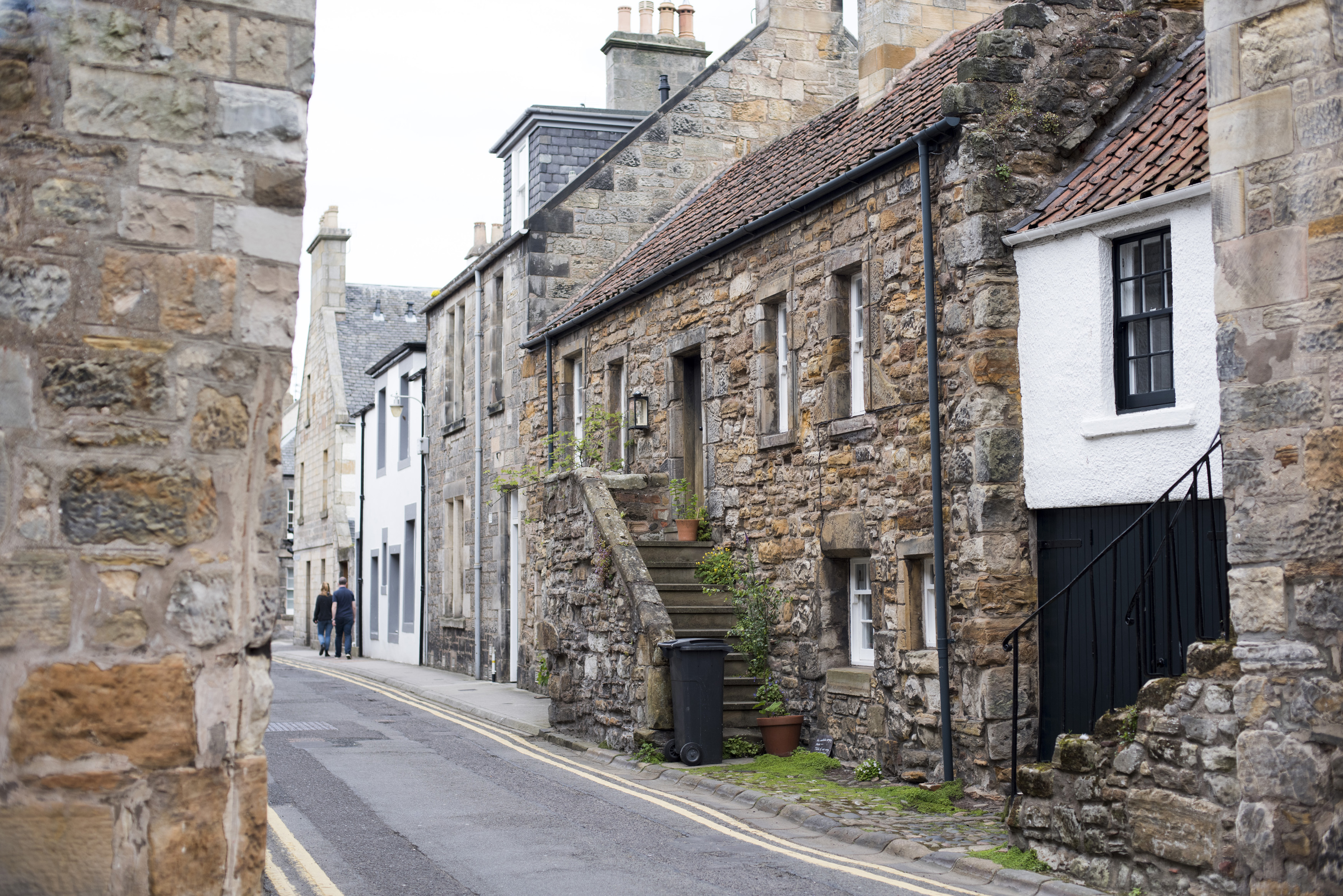 an image of Narrow street lined with stone walled houses in little village at Saint Andrews, Scottland