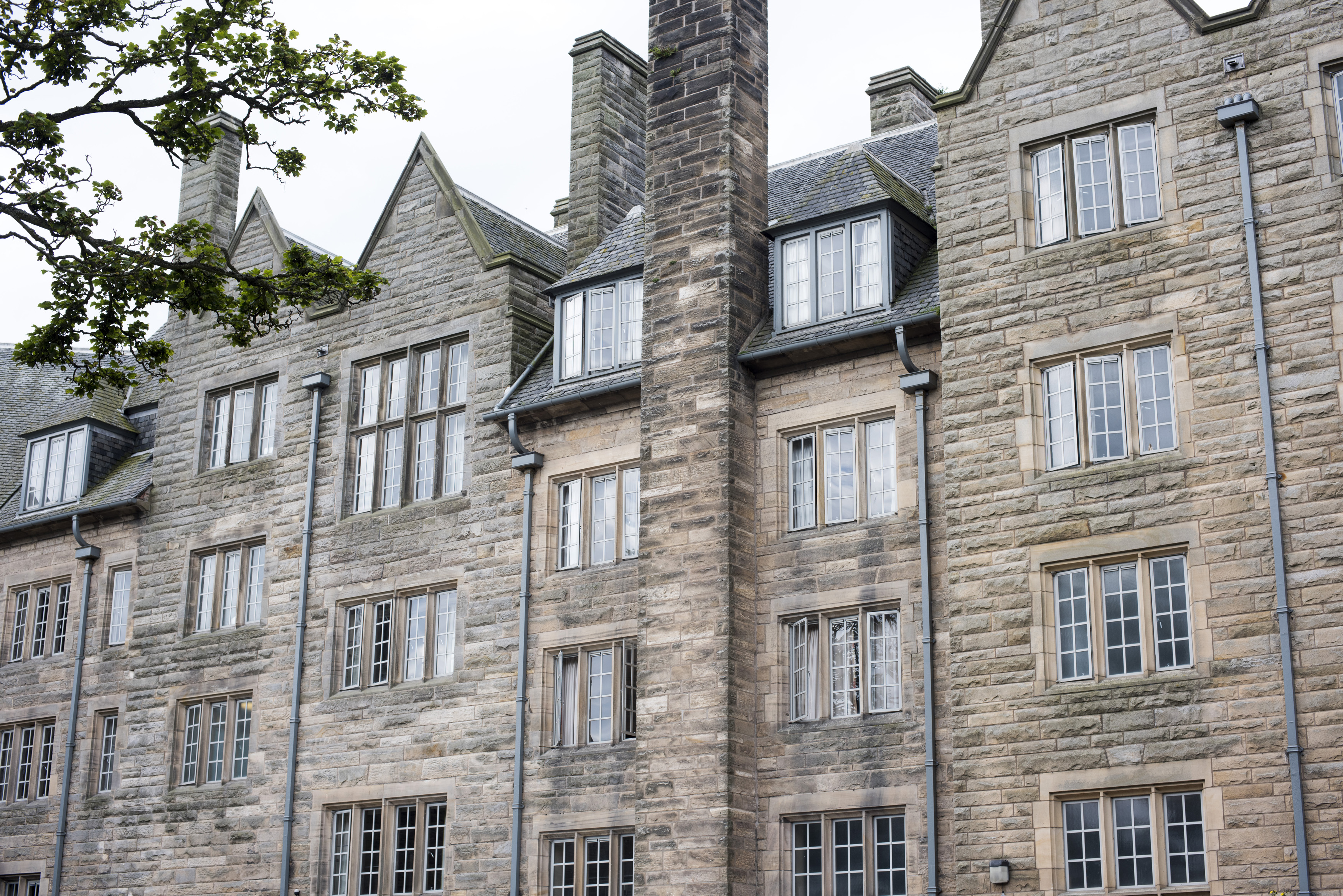 an image of Four story apartments with old stone walls and casement windows in Saint Andrews, Scotland