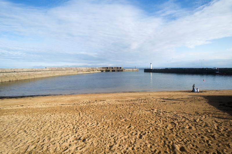 Marine harbour Anstruther, Scotland at low tide looking out towards the entrance and lighthouse beacon
