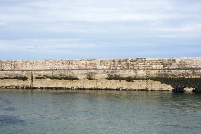 Seawall on the harbour or marina, Anstruther, Scotland with sheltered water in the foreground for safe mooring