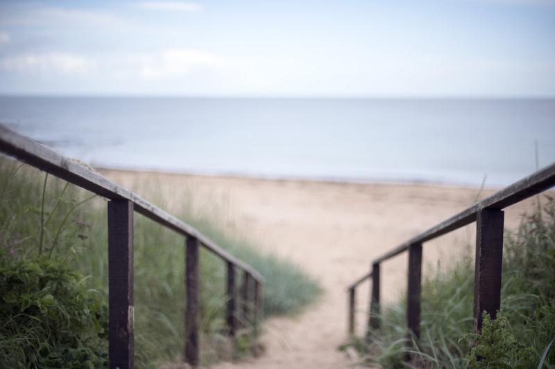 Stairs descending to the sandy beach and calm ocean on the Fife coast in Scotland, UK in a landscape view