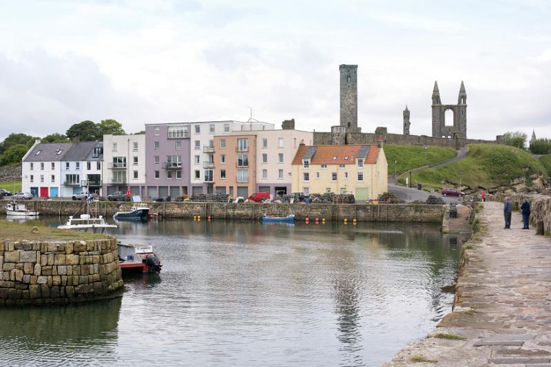 Cute little European fishing harbor with quaint storefronts and apartments near Saint Andrews cathedral ruins in Scotland