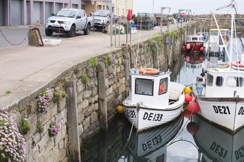 Pair of little white tug boats in low tide water at famous landmark Saint Andrews pier in Scotland