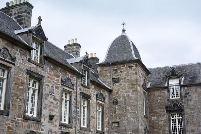 Ancient architecture of St Andrews University, Scotland with a close up view of a corner tower, upper floor windows and rooftop