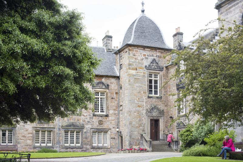 Students in the grounds of St Andrews University, Scotland sitting and walking in front of the ancient historic stone buildings