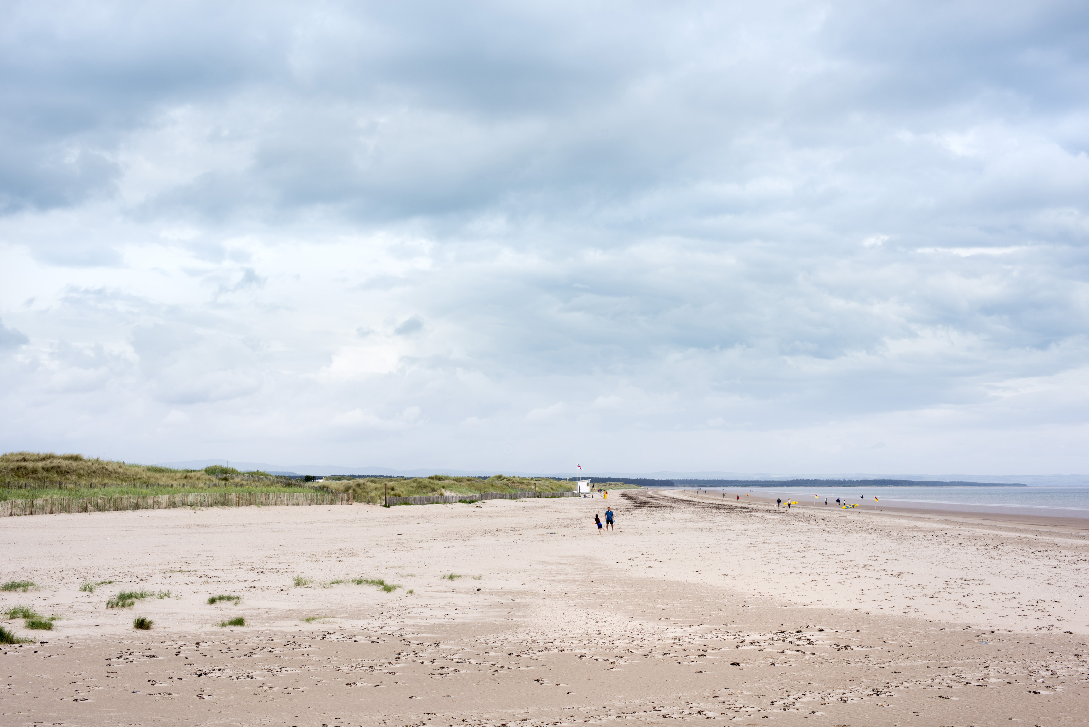an image of Wide open sandy beach with trails of footprints under cloudy sky at Saint Andrews, Scotland