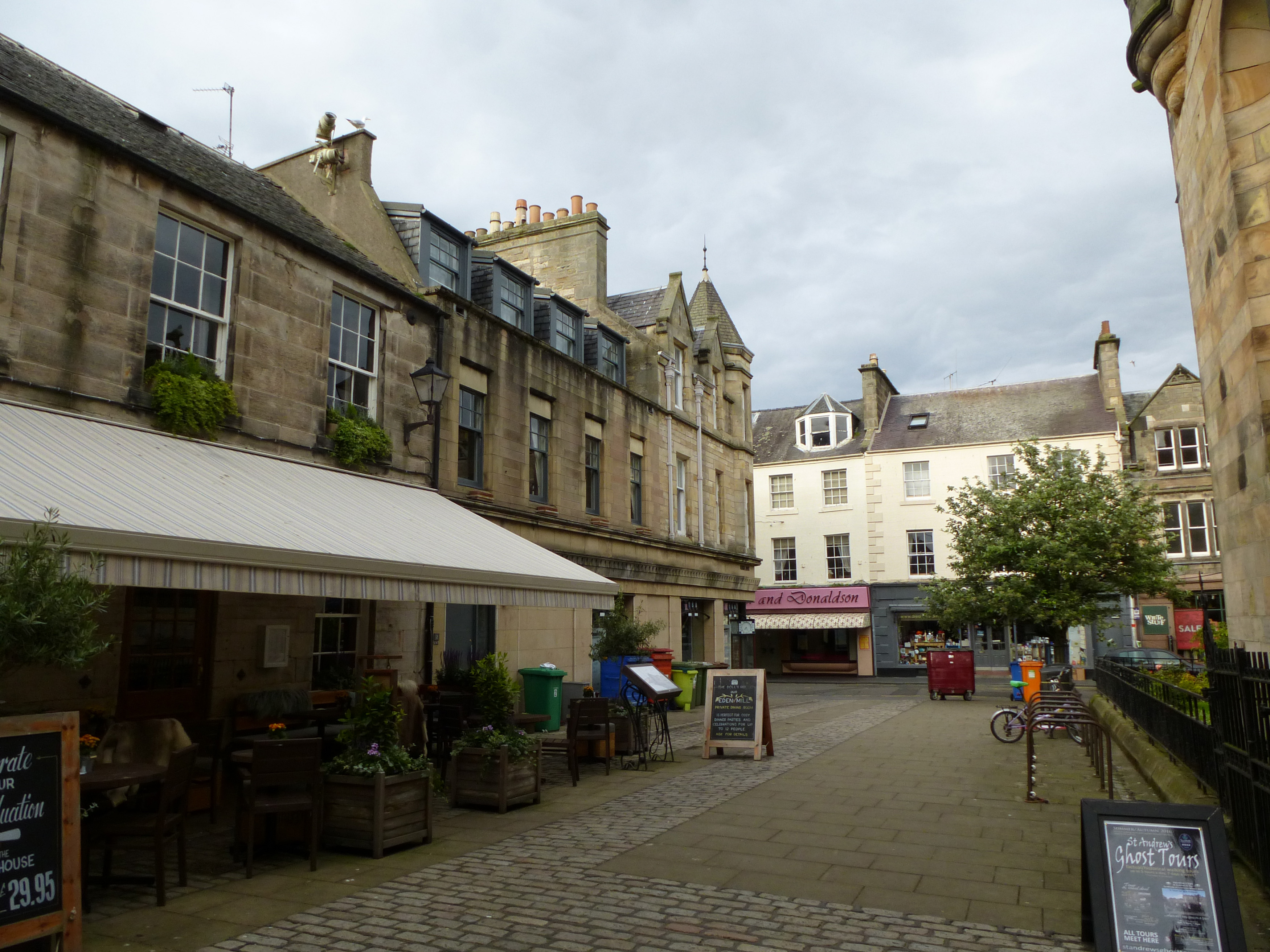 an image of Open air restaurant on cobblestone street in quaint business area of Saint Andrews, Scotland