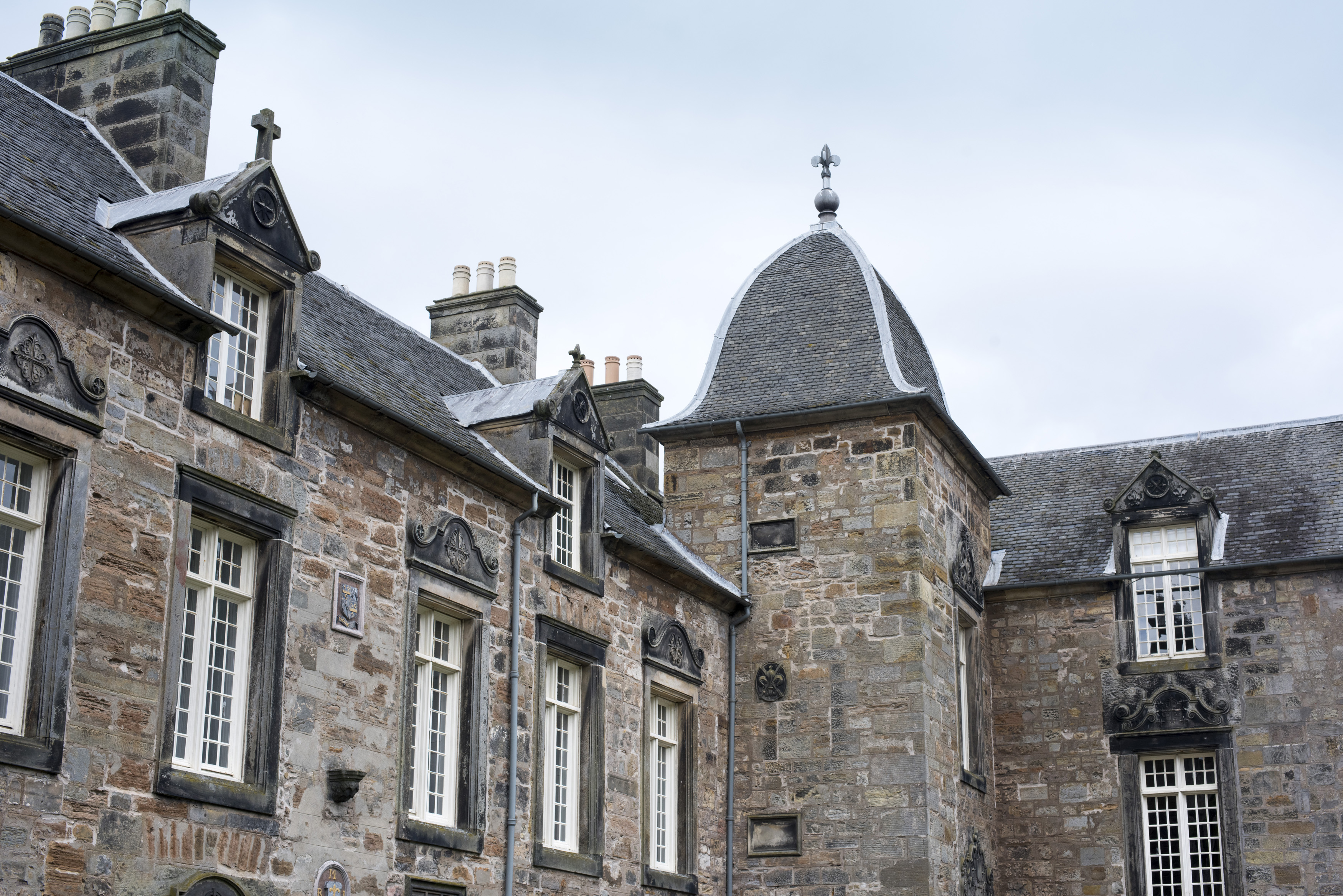 an image of Ancient architecture of St Andrews University, Scotland with a close up view of a corner tower, upper floor windows and rooftop