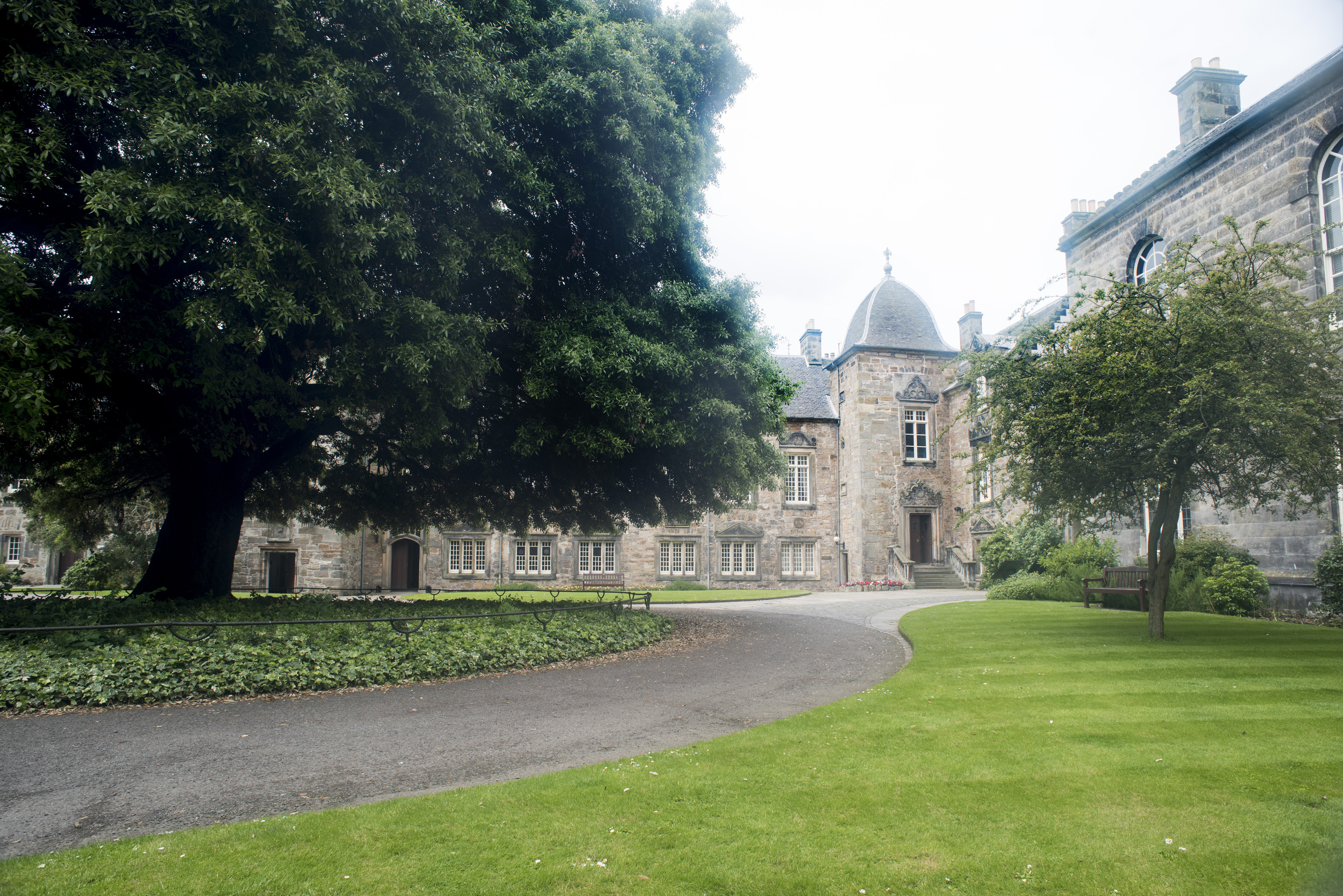 an image of Paved asphalt winding walkway leading to little corner section of University of Saint Andrews in Scotland