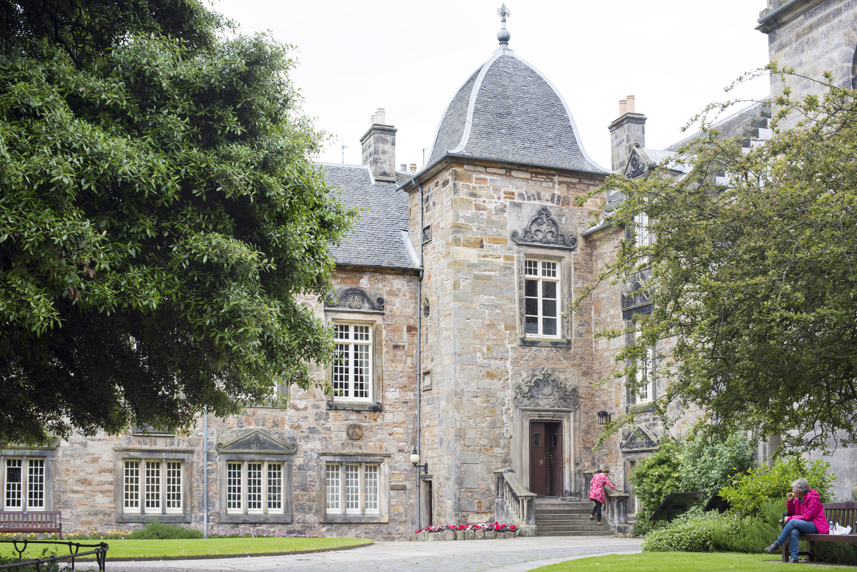 an image of Students in the grounds of St Andrews University, Scotland sitting and walking in front of the ancient historic stone buildings