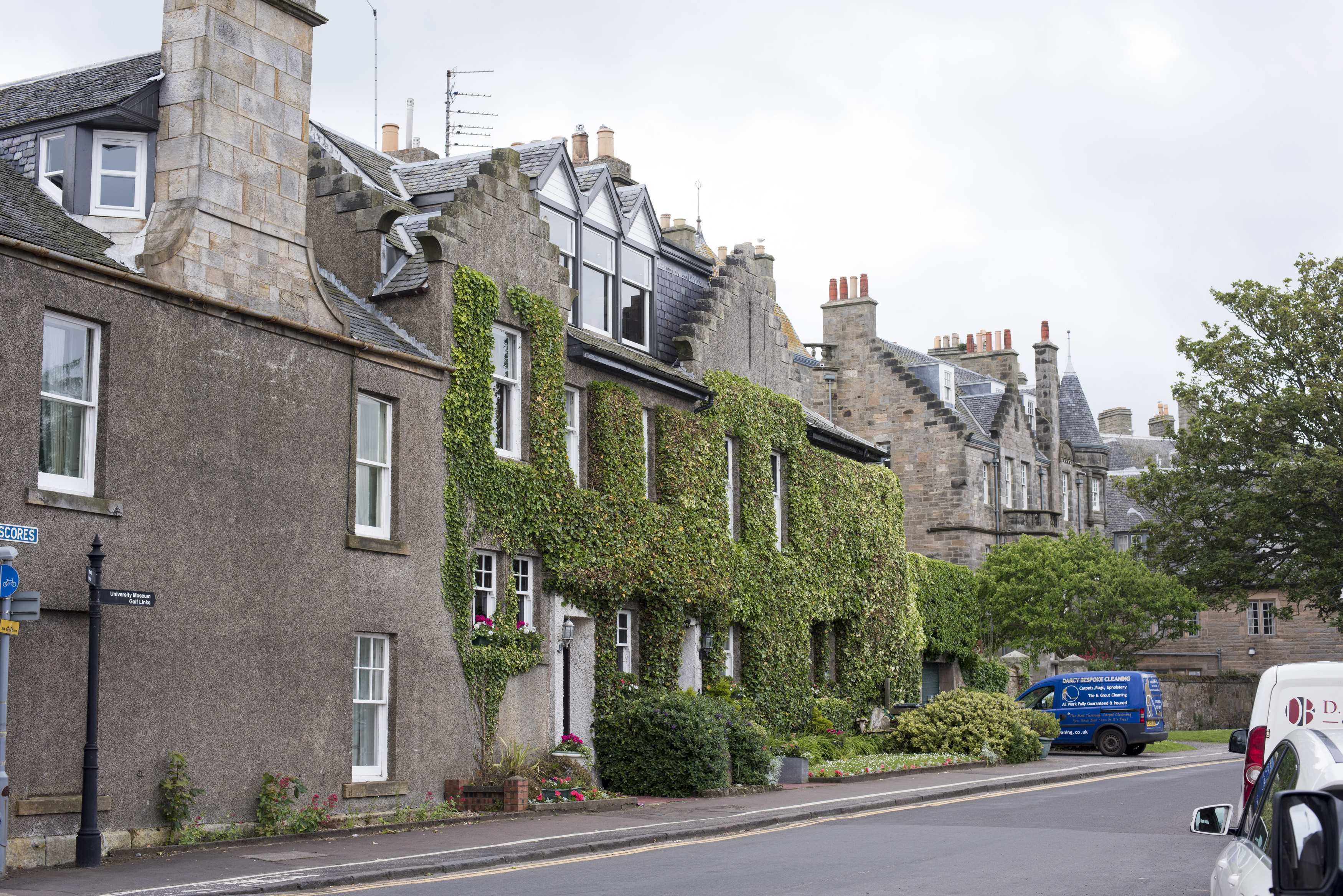 an image of Pleasant Scottish city of Saint Andrews with vines growing on the side of the stone buildings