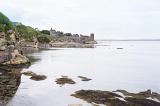 View of ocean and rocky beach under overcast sky at old fishing harbor in Saint Andrews, Scotland