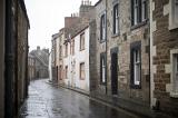 Empty brick road on rainy day in old village lined with stone apartment houses in Scotland