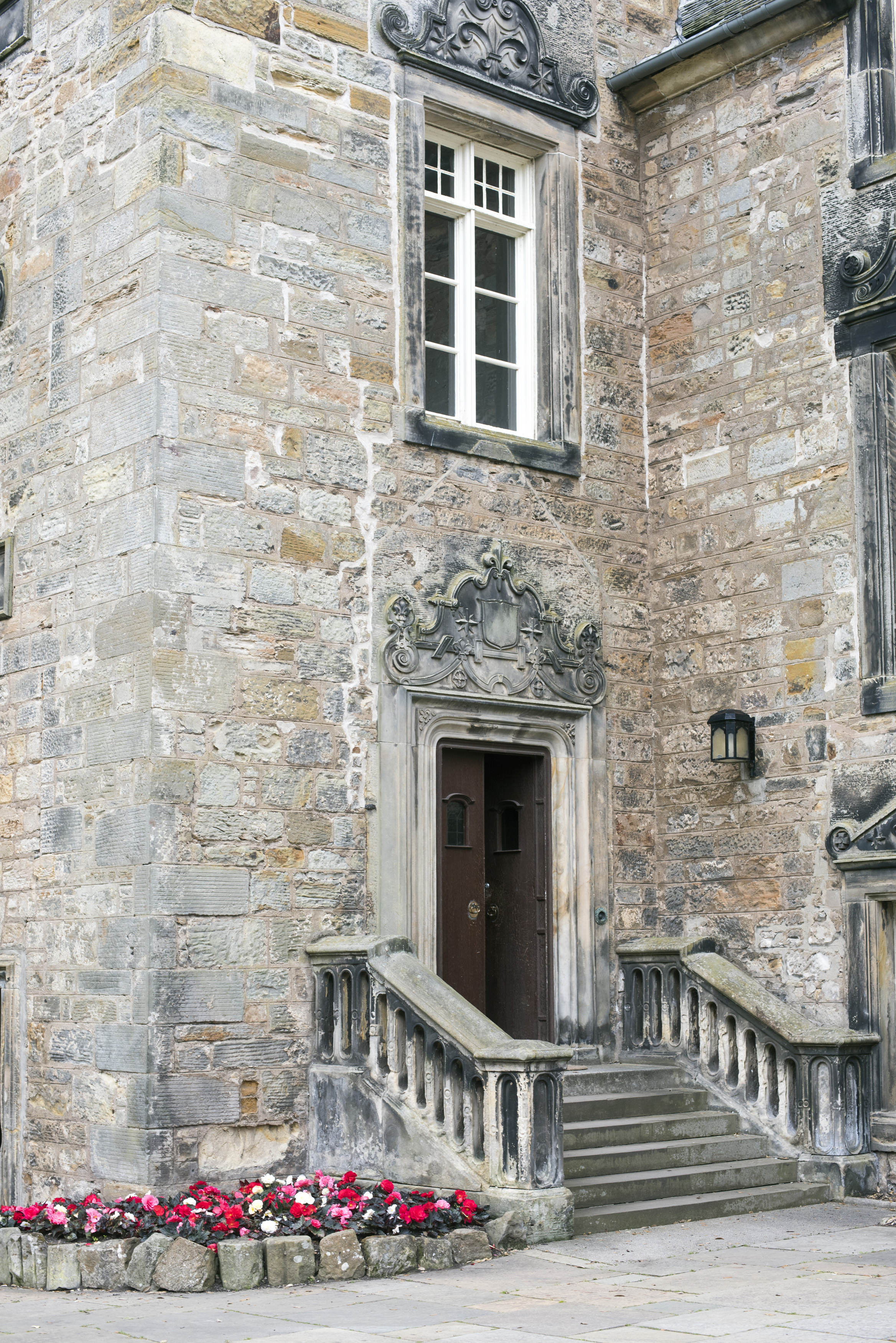 an image of Stone stairway with little annual white, pink and red flowers at University of Saint Andrews in Scotland