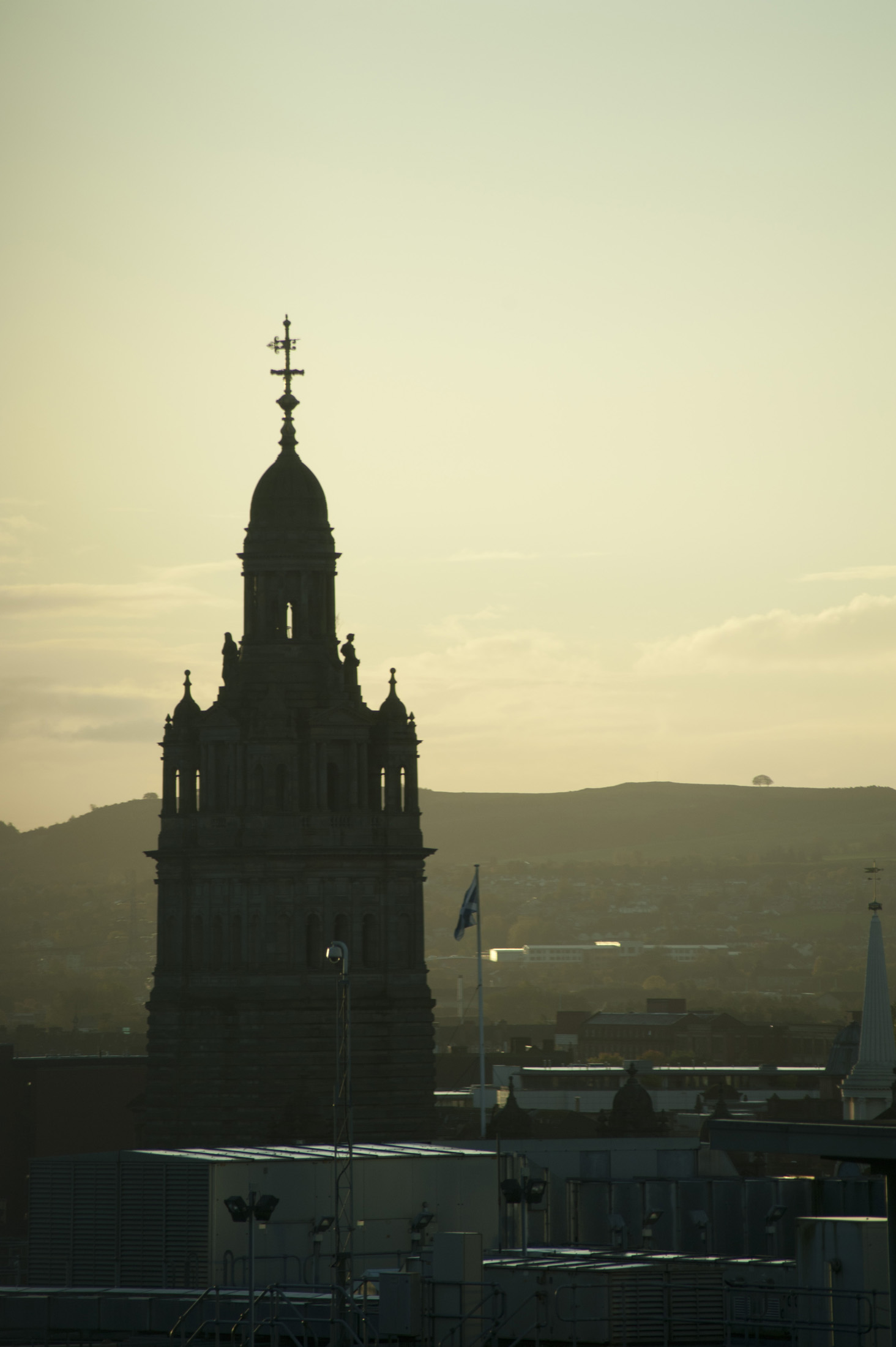 an image of Glasgow City Hall silhouette at dusk towering over the rooftops of the city against a glowing horizon