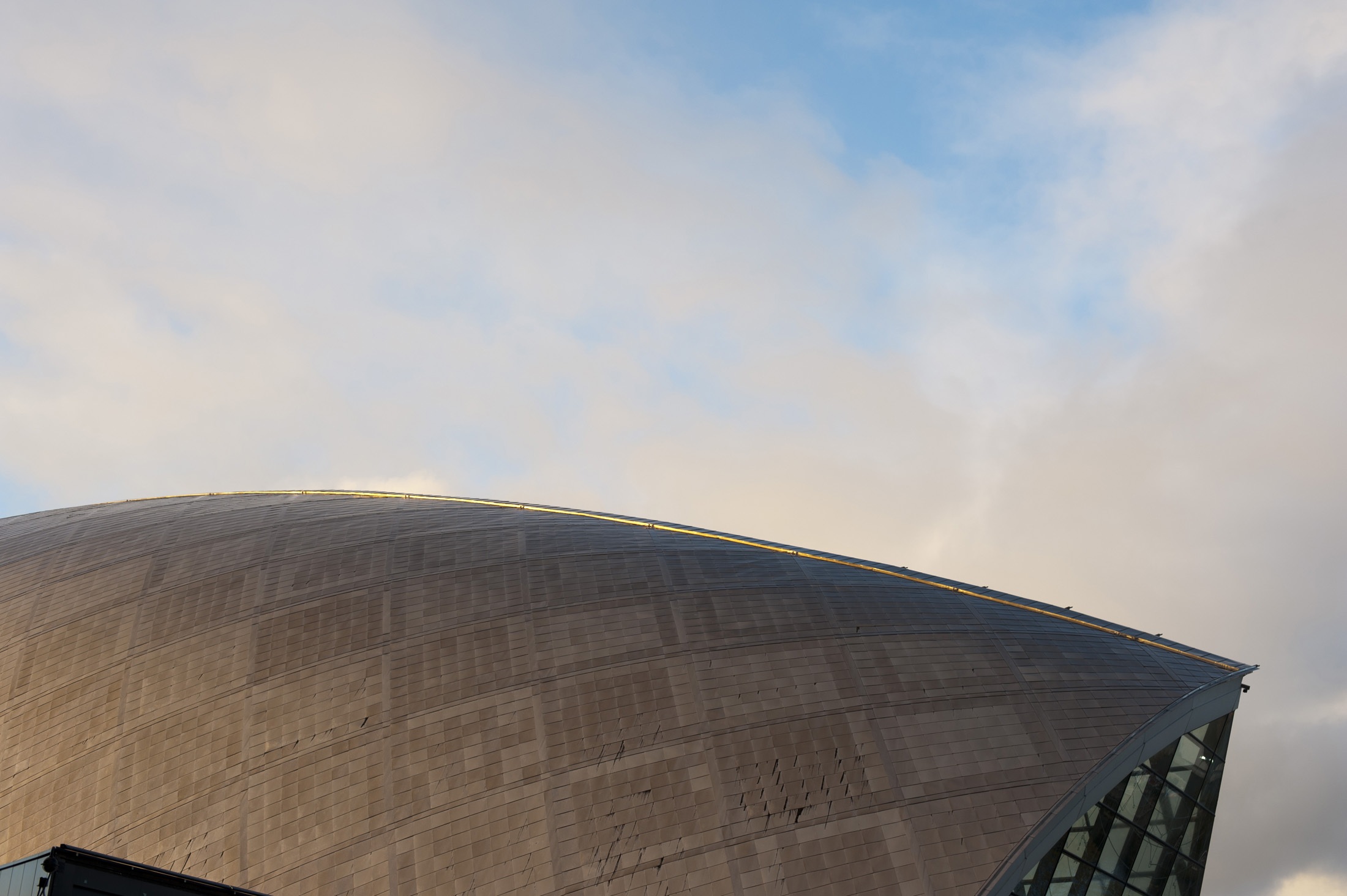 an image of Detail of the architecture of the external facade of the Glasgow Science Centre with its distinctive domed metal structure against a blue sky
