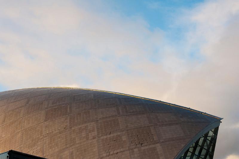 Detail of the architecture of the external facade of the Glasgow Science Centre with its distinctive domed metal structure against a blue sky