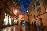 Entrance to Royal Exchange Square, Glasgow at night with illuminated shop windows and rows of overhead Christmas lights