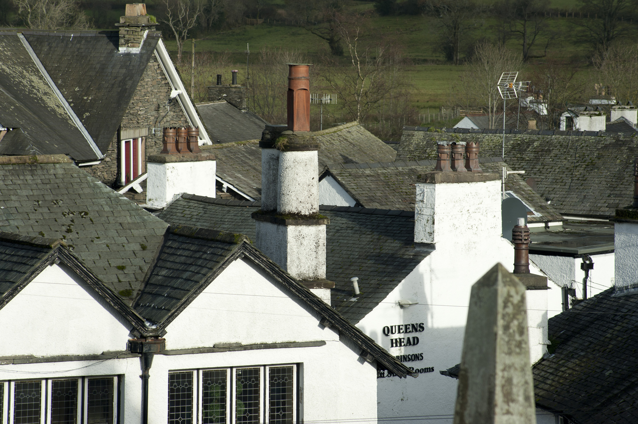 an image of quaint white painted housed and cumbrian slate roofs with fields beyond