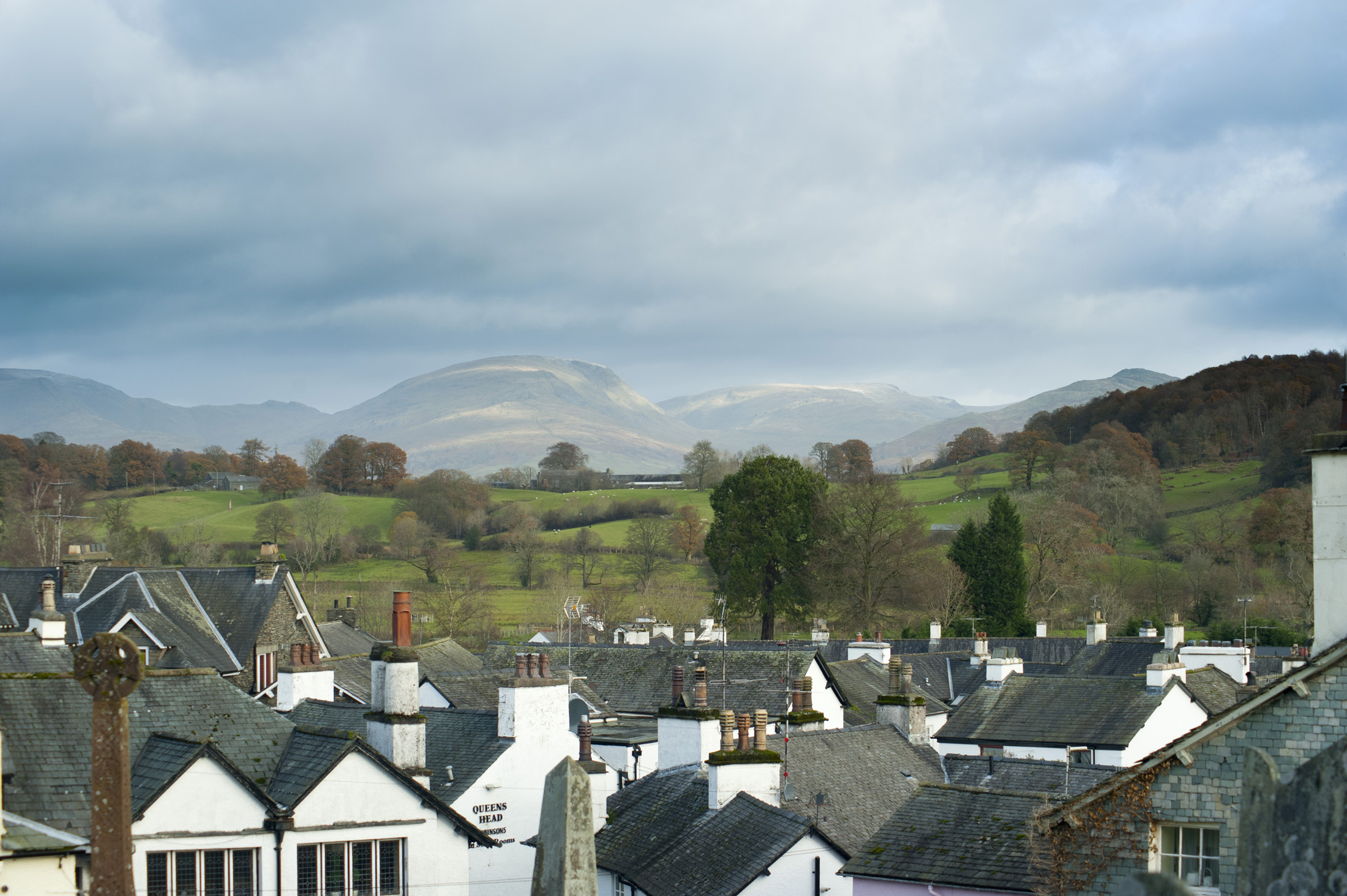an image of View over the rooftops of the quaint village of Hawkshead in the English Lake District with its picturesque whitewashed cottages to the countryside beyond