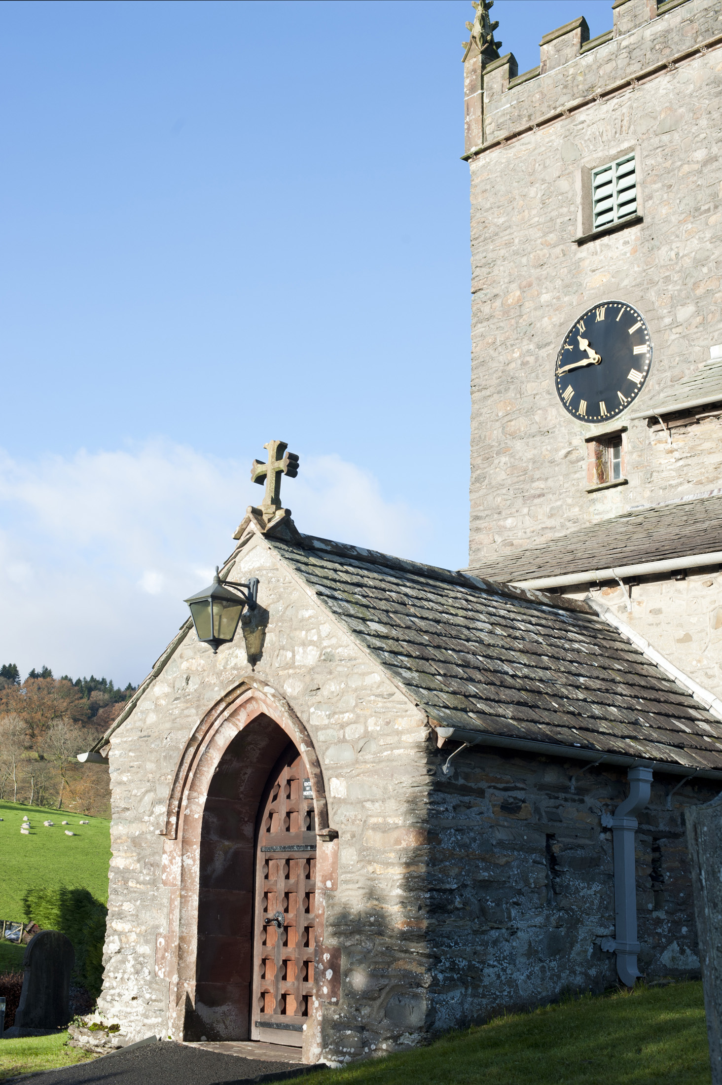 an image of Entrance to St Michael and All Angels stone church in the quaint village of Hawkshead in the Lake District in Cumbria, England