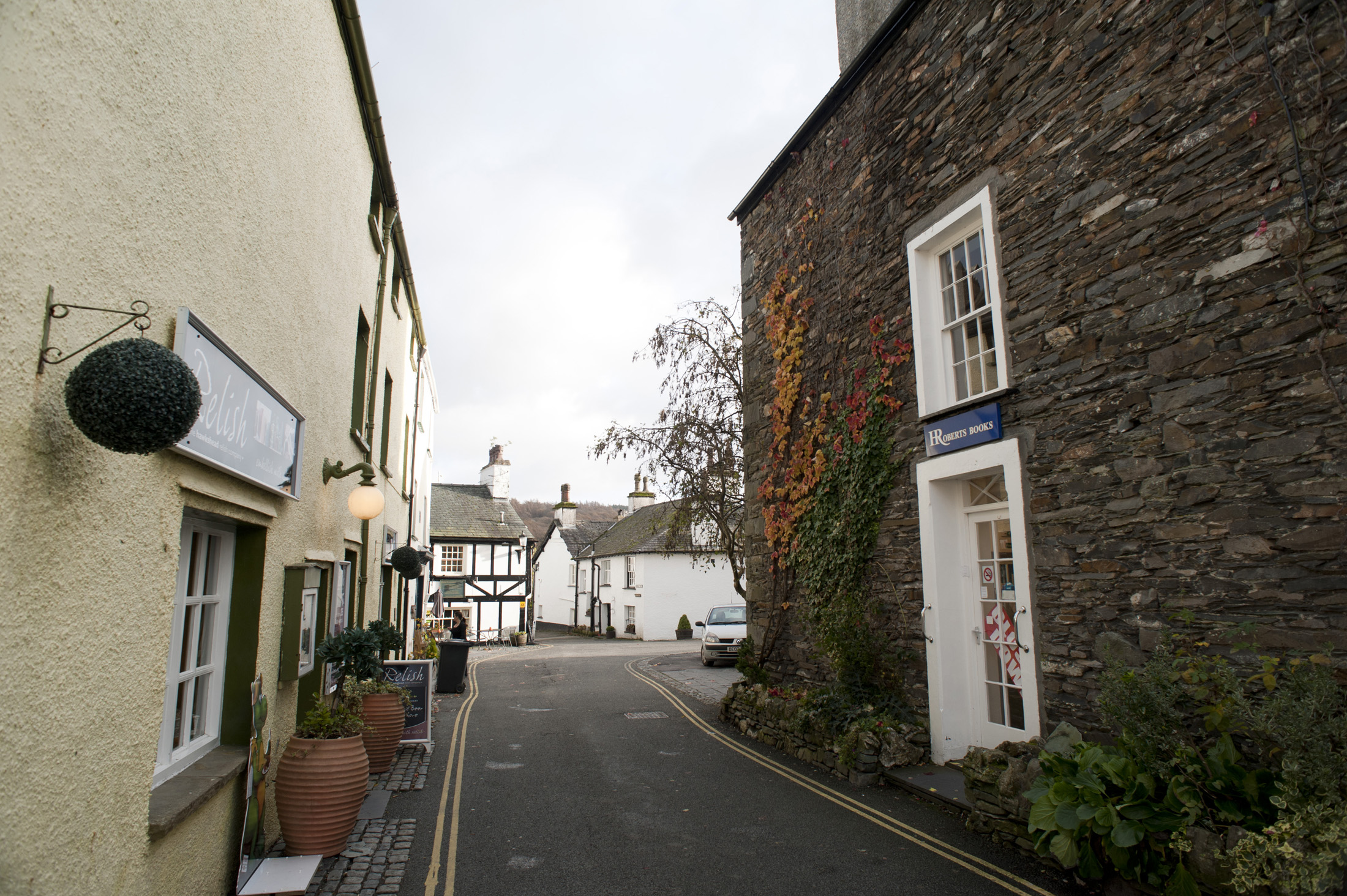 an image of Narrow street in Hawkshead village, Cumbria lined with historical stone cottages typical of the architecture of the English Lake District