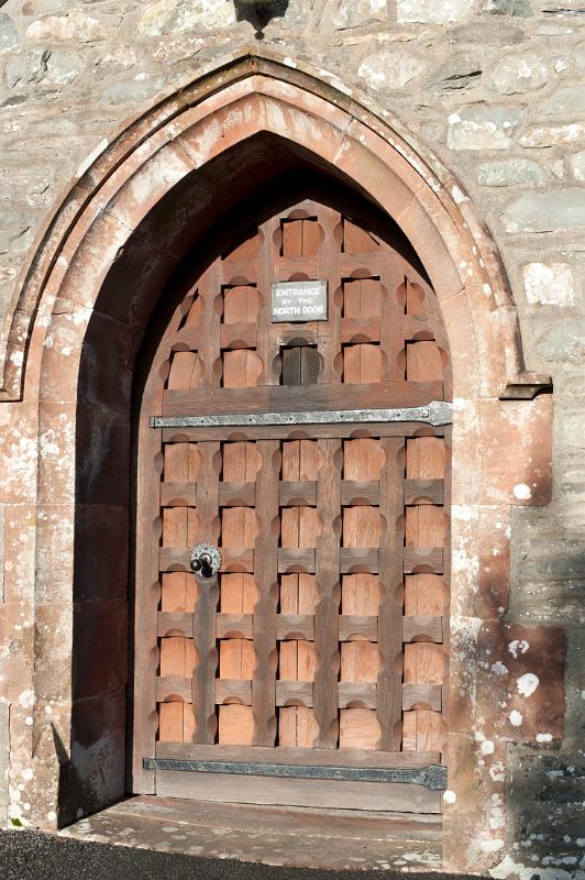 Arched medieval wooden entrance door to St Michaels and All Angels Church in the village of Hawkshead in the Lake District in Cumbria