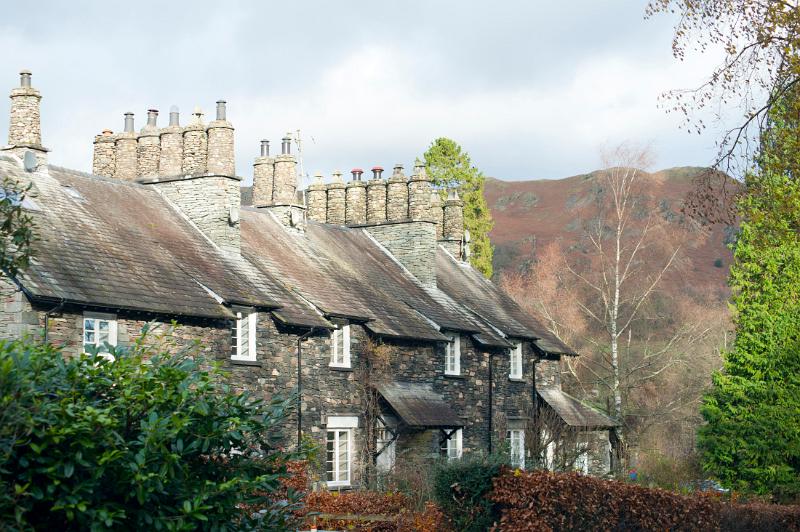 Picturesque row of English stone cottages at Skelwith Bridge in the Lake District in Cumbria with traditional round stone chimney pots