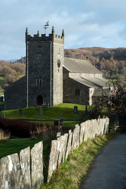 View down a country lane of Hawkshead church in the picturesque village of Hawkshead in the English Lake District in Cumbria and a popular tourist destination
