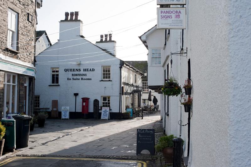 Queens Head Hotel in Hawkshead, Lake District,Cumbria view looking up a quaint narrow road with the sign visible on the whitewashed wall