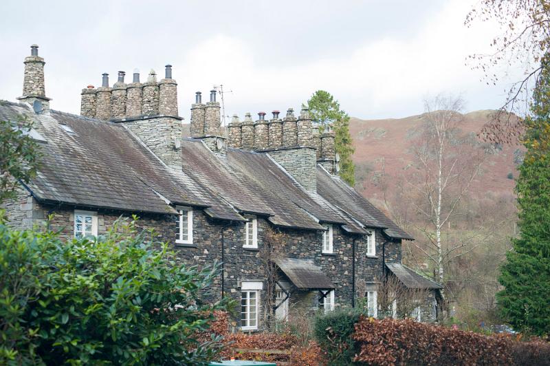 Row of quaint Cumbrian stone cottages at Skelwith Bridge with cylindrical stone chimney pots and neat front gardens