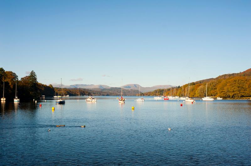 yachts moored on the calm waters of windermere, cumbria lake district with a clear blue sky