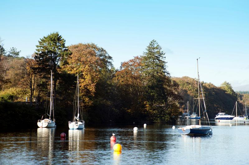 Yachts moored on buoys on the calm water of Windermere Lake in the Lake District in Cumbria