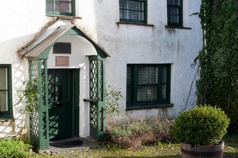 Covered front entrance to a small traditional whitewashed picturesque cottage in Hawkshead, a popular tourist destination in the Lake District