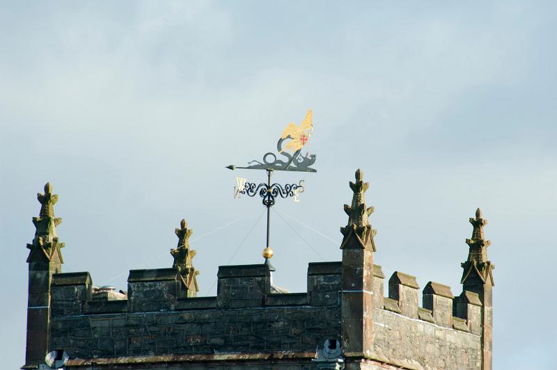 Weathervane to follow the direction of the wind on Hawkshead Church clock tower with its crenellated walls and distinctive corner ornamentation