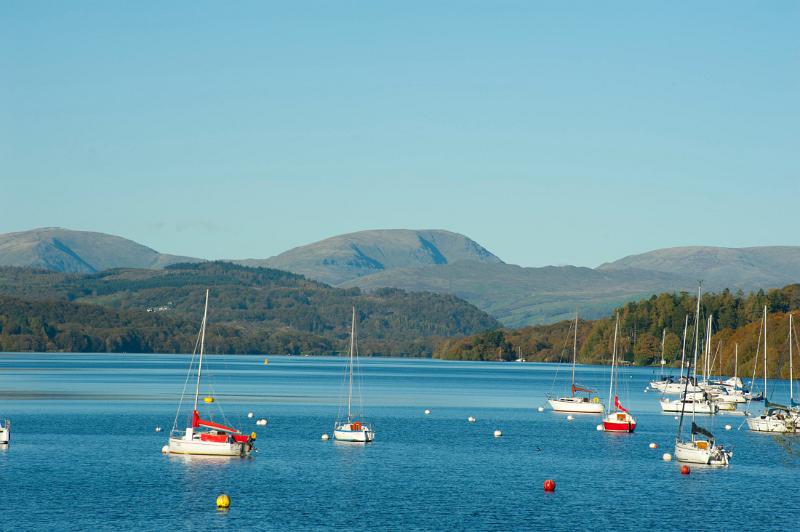 Pleasure yachts moored on the calm water of Lake Windermere in the Lake District in Cumbria against a mountain backdrop