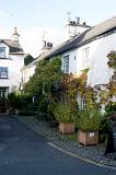 Whitewashed cottages in Hawkshead in a narrow street lined with potted plants and creepers in this picturesque village in the Lake District in Cumbria